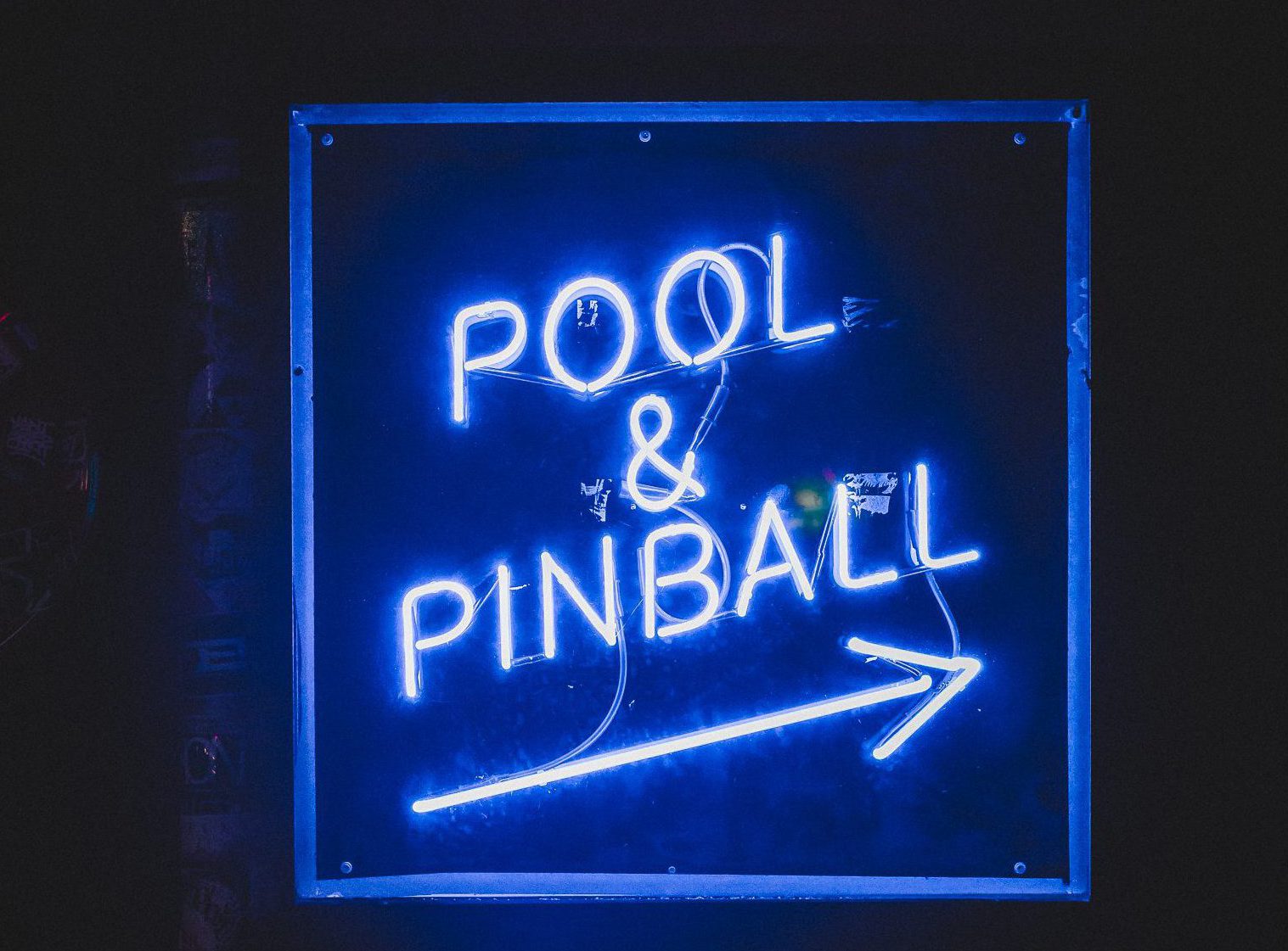 Blue neon sign that reads "pool and pinball."